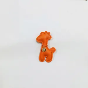 Close-up of an orange leather giraffe charm with a gold chain and pendant