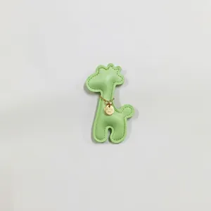 Detail view of a cute light green leather giraffe charm with decorative gold chain