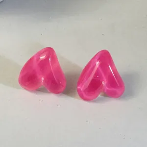 Close-up of bright pink translucent candy-colored heart earrings with resin texture