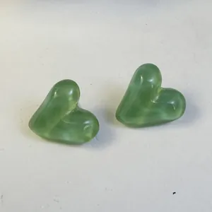 Detailed macro view showing the translucent candy-colored green heart stud earrings