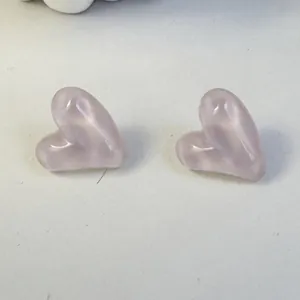 Close-up detail of candy-colored pink heart-shaped stud earrings with smooth finish