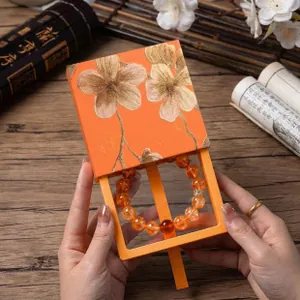 Detailed close-up of an elegant orange floral jewelry gift box with a beaded bracelet