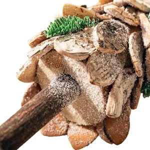 Close-up of a wooden Christmas tree ornament with birch bark shingles and frosted snow finish