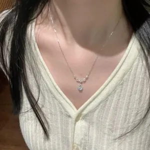 Elegant silver necklace with a blue crystal heart pendant worn on a white ribbed cardigan