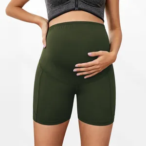 Detailed front view of dark green high-waisted maternity yoga shorts showing belly support
