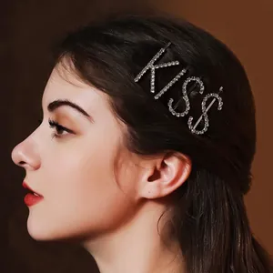 Elegant silver rhinestone letter hair clip spelling KISS worn by a model in profile view