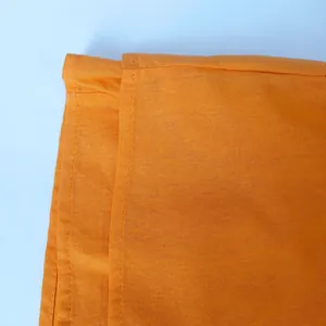 Close-up detail of orange linen-textured fabric with durable stitching on casual wear.