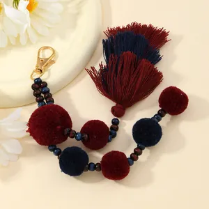 Dettaglio di portachiavi con pompon di peluche con nappe bordeaux e blu scuro