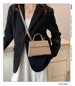 Khaki crocodile texture handbag with gold-tone lock shown on model as shoulder bag