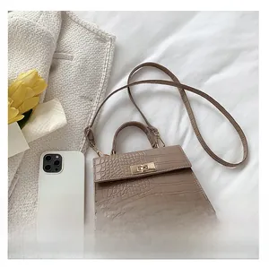 Detailed view of a taupe crocodile pattern small handbag with elegant gold twist lock detail
