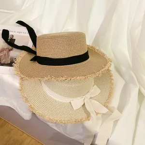 Detail view of straw sun hats with contrasting ribbon bows and stylish frayed edges.