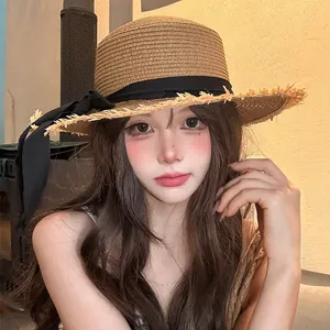 Close-up of a women's straw sun hat featuring a large brim and elegant black bow ribbon