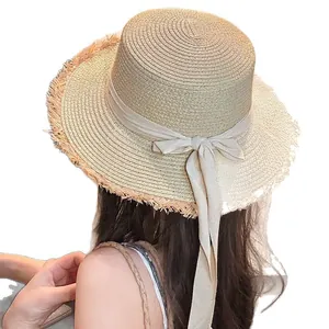 Elegant women's straw sun hat with a large lace bow and frayed brim for beach vacation