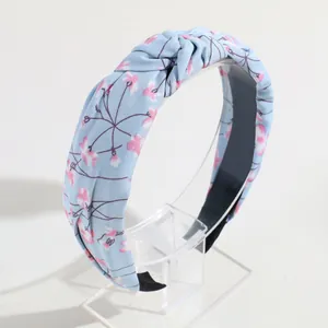 Elegante cerchietto annodato azzurro con motivo floreale rosa su supporto in acrilico