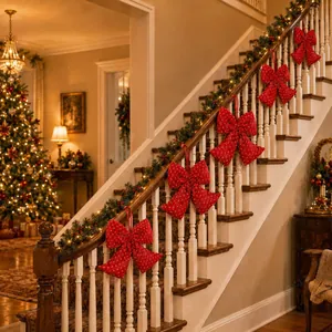 Large red polka dot Christmas bow ornaments hung on a garland-decorated staircase