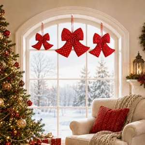 Red Christmas bow ornaments hanging on a window in a cozy winter living room