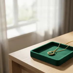 Close-up view of a U-shaped gold necklace with an emerald stone in a jewelry tray