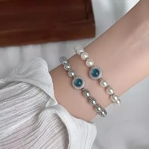 Detailed view of elegant pearl and silver beaded bracelets with blue crystal charm