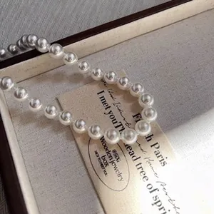 Close-up detail of an elegant white pearl bracelet resting in a wooden jewelry gift box.