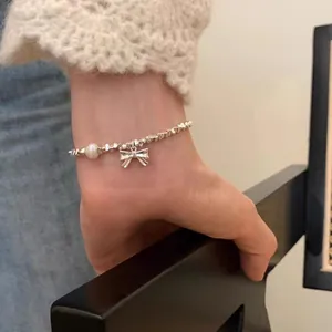 Detail view of S925 sterling silver bracelet with pearl and bow pendant on wrist