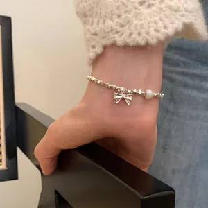 S925 sterling silver bracelet featuring a bow charm and heart pearl on a model's wrist