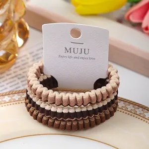 Set of three coffee brown pleated elastic hair ties presented on a white display card