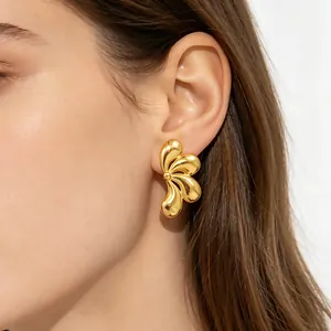 Boucles d'oreilles clous dorées élégantes en forme de pétale sur l'oreille d'un modèle