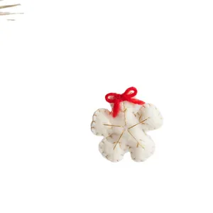 Handmade wool felt snowflake ornament with red bow for Christmas tree decoration.