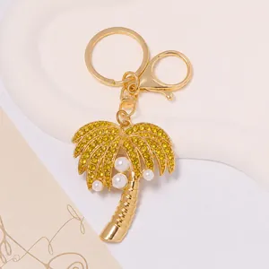 Close-up detail of a golden palm tree keychain with yellow rhinestones and pearls