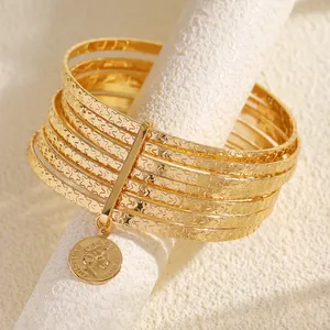 Close-up of vintage gold bangle set with star texture and coin pendant detail