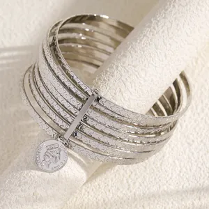 Detailed view of silver stackable alloy bangles with star pattern and coin charm pendant.