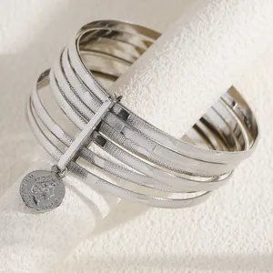 Detail shot of multi-layer silver-tone bangles with Queen Elizabeth II coin charm
