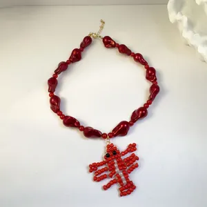 Close-up detail of a vibrant red beaded necklace featuring a handcrafted lobster pendant
