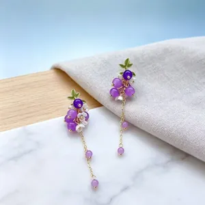 Boucles d'oreilles pendantes grappe de raisin violette avec longues chaînes dorées.