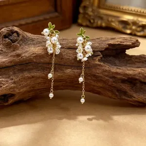 Boucles d'oreilles pendantes en perles avec feuilles vertes sur un socle en bois