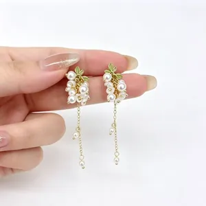 Gros plan détaillé de boucles d'oreilles grappes de perles avec glands à la main