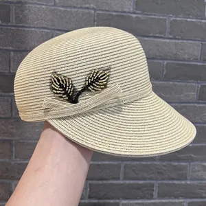 Detail shot of an elegant beige straw hat featuring exquisite beaded leaf decoration