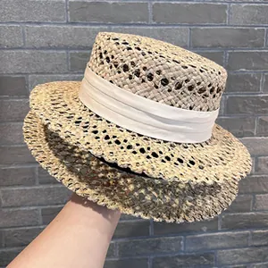 Detail side view of an elegant woven straw hat with flat top and white ribbon band