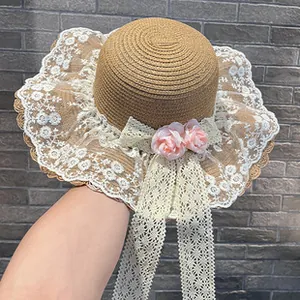 Close-up of women's flat top straw sun hat with elegant white lace trim and pink roses