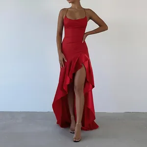 Detail shot of an elegant red satin evening gown featuring a high slit and ruffled hemline.