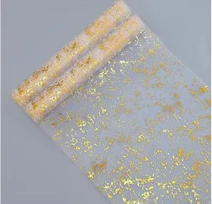 Macro detail of white mesh table runner with sparkling gold foil splash pattern