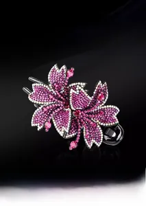 Gros plan d'une pince à cheveux florale avec strass roses et blancs sur fond noir