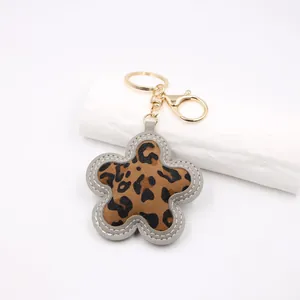 Close-up of leopard print flower keychain with gold-tone metal clasp and grey stitching