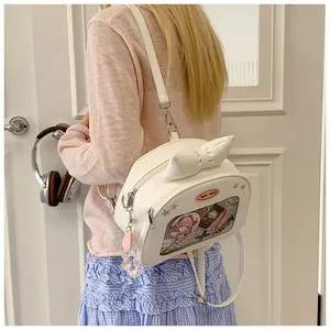 Close-up of white Ita bag with large bow and clear window showing anime accessories