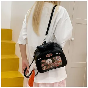 Close-up of black leather ita bag with a large bow, clear window and heart charm