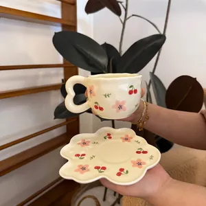 Detailed close-up of handmade floral ceramic coffee cup with irregular heart handle