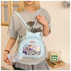 Detail of light blue ita bag with transparent PVC window showing anime badges and bow