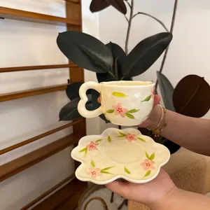 Detail of ceramic coffee cup with heart handle and floral petal saucer set