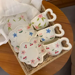 Floral ceramic coffee cup set with heart handles and petal saucers in a woven basket