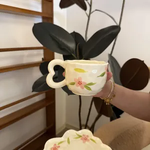 Detail of hand-painted floral ceramic coffee mug with a unique heart-shaped handle